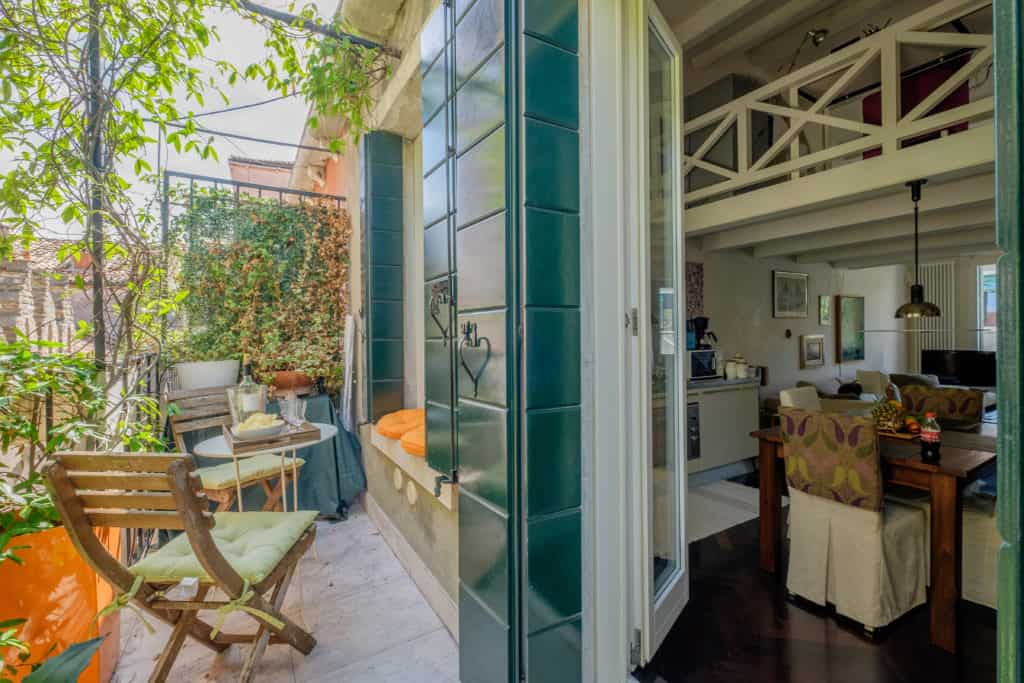 Exit door of small terrace with small dining table and cushions - Attico Terrace Apartment